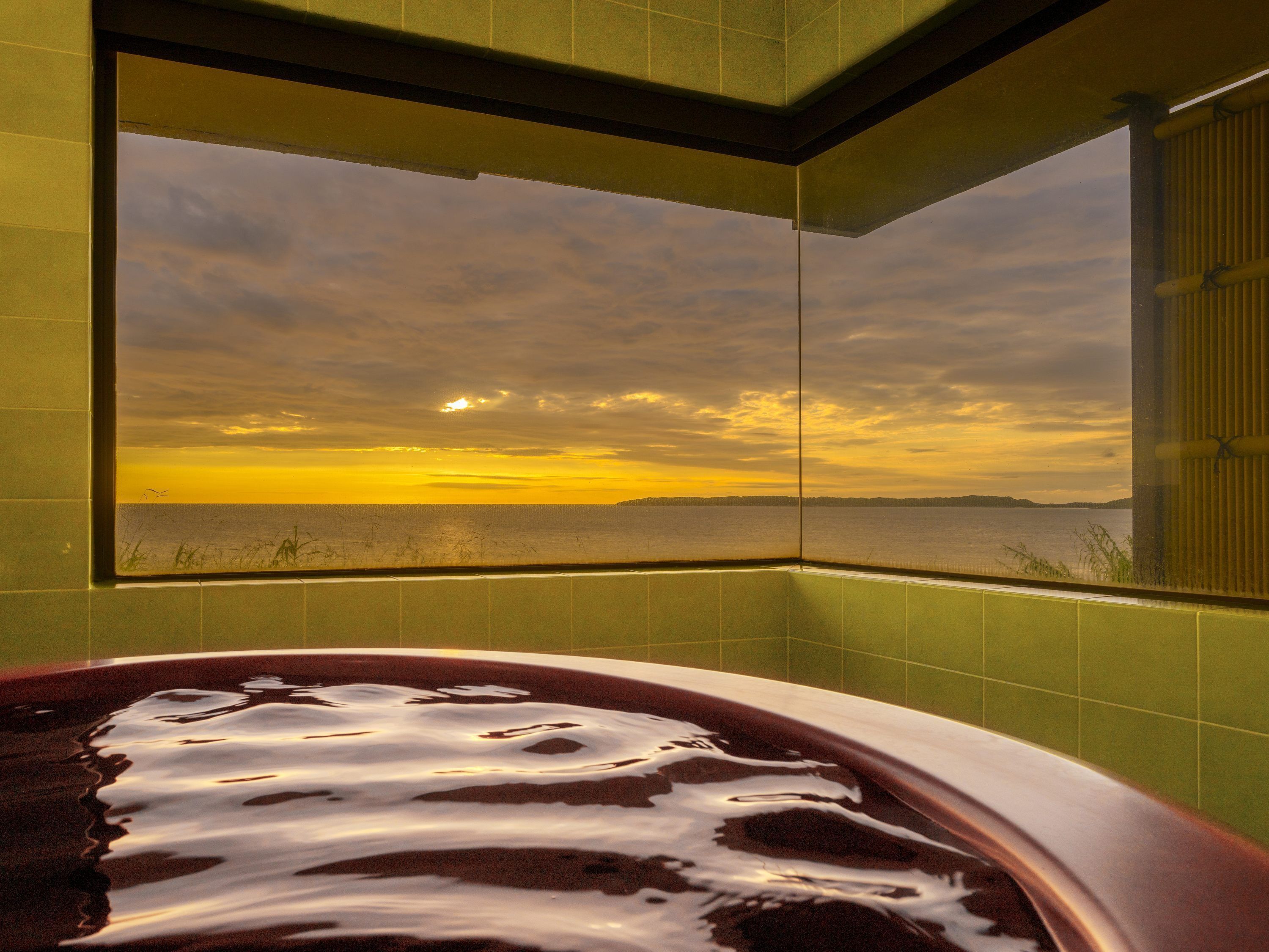 A bathtub with a view of a sunset over a body of water.
