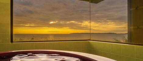 Una bañera con vista a un atardecer sobre el agua.