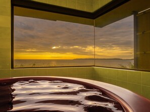 Une baignoire offrant une vue sur un coucher de soleil se reflétant sur une étendue d’eau.