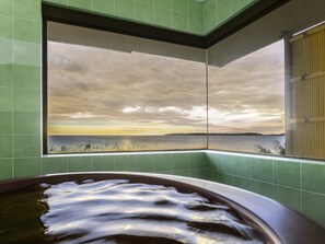 Une baignoire donnant sur un plan d’eau et un ciel nuageux.