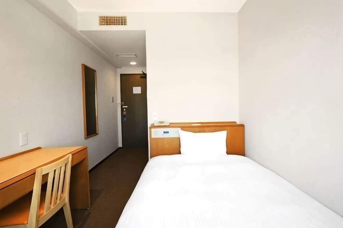 Una habitación de hotel con una cama, un escritorio y una silla.