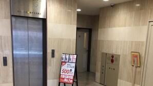 A clean, modern elevator area with a sign advertising a 500-point membership card. - Smile Hotel Sugamo (Tokyo)