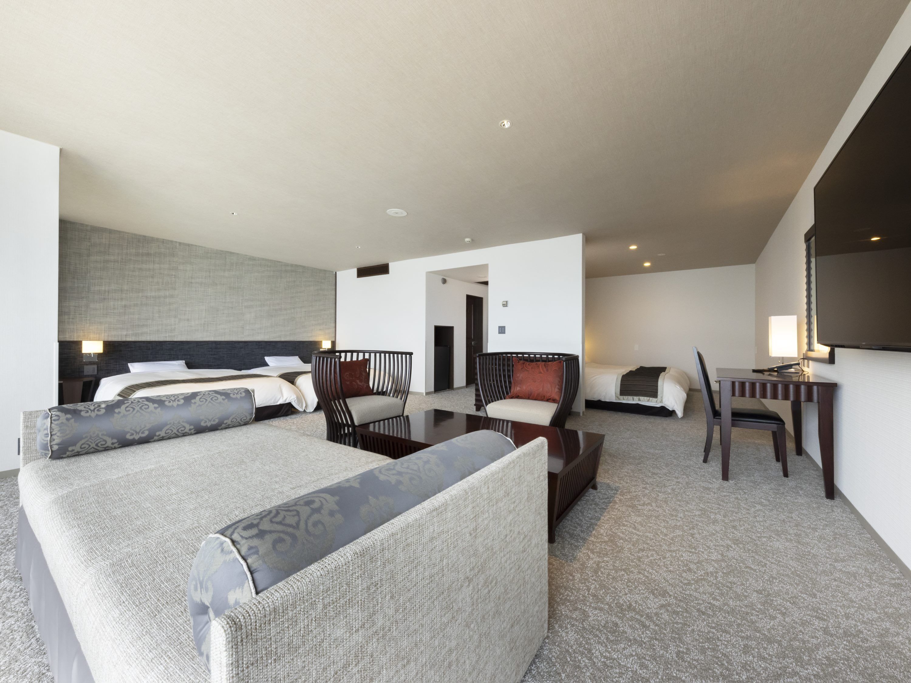 A hotel room with a large bed, a sofa, a desk, and a chair.