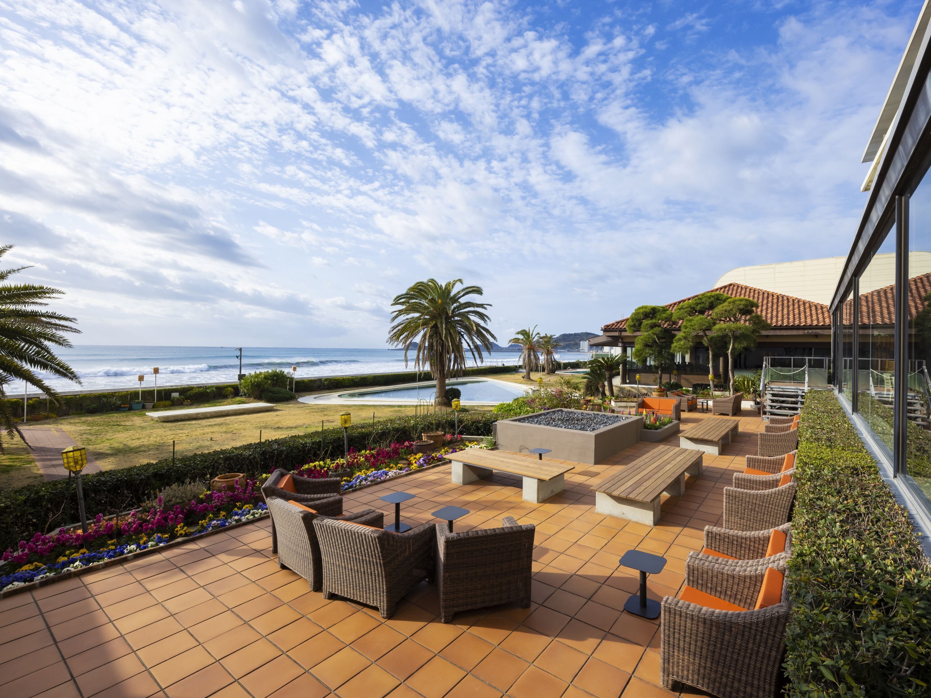 A patio with outdoor furniture, a swimming pool, and a view of the ocean.