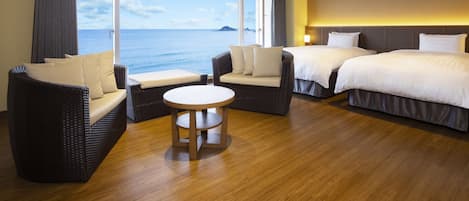 A hotel room with a large window, two beds, a round table, and wicker furniture.