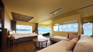 Ein modernes Hotelzimmer mit einem großen Bett, einer Sitzecke, einem kleinen Tisch und Blick aufs Meer.
