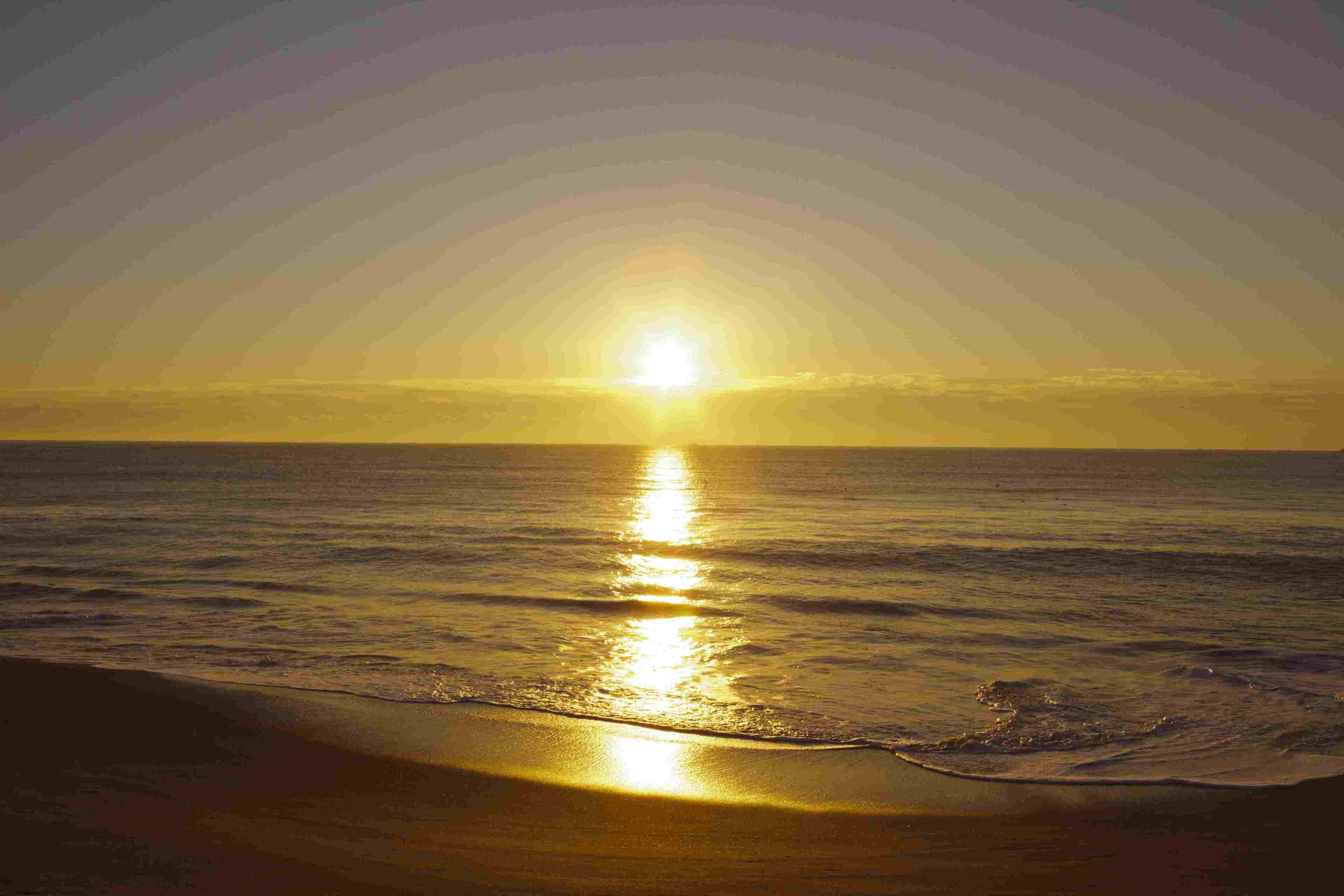 A sunset over the ocean with the sun reflecting on the water.