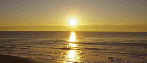 A sunset over the ocean with the sun reflecting on the water.