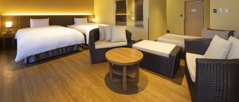 A hotel room with two beds, a sofa, a round table, and a window.