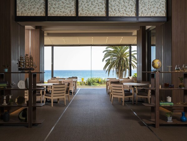 A modern interior with a view of the ocean, featuring wooden furniture, a globe, and a ship model. - Kamogawa Grand Hotel (Kamogawa)