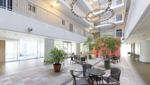 A spacious indoor area with multiple levels, potted plants, and seating arrangements. - Katsuura Hilltop Hotel & Residence (Katsuura)