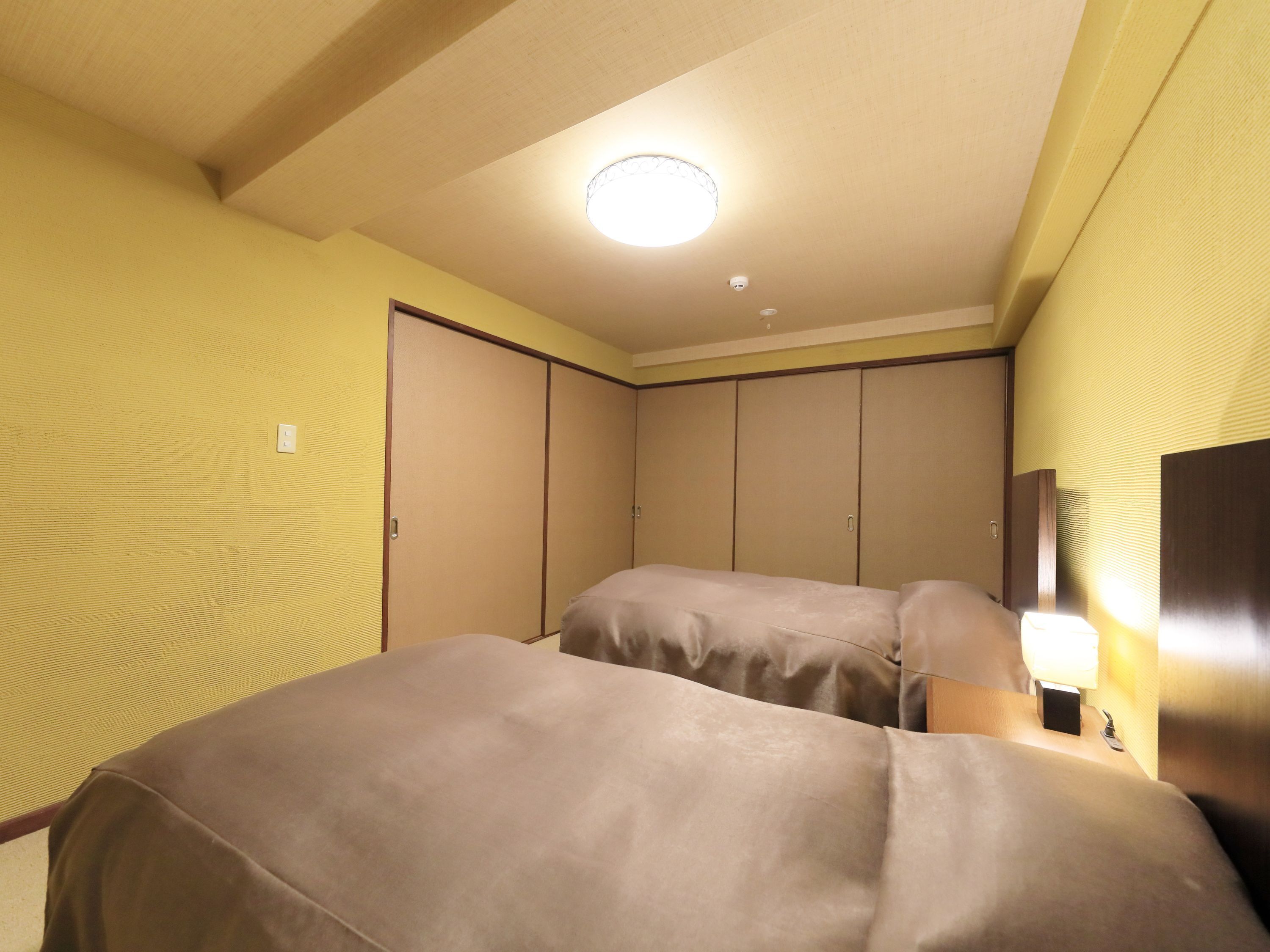 Una habitación de hotel con cama, armario y mesita de noche con lámpara.