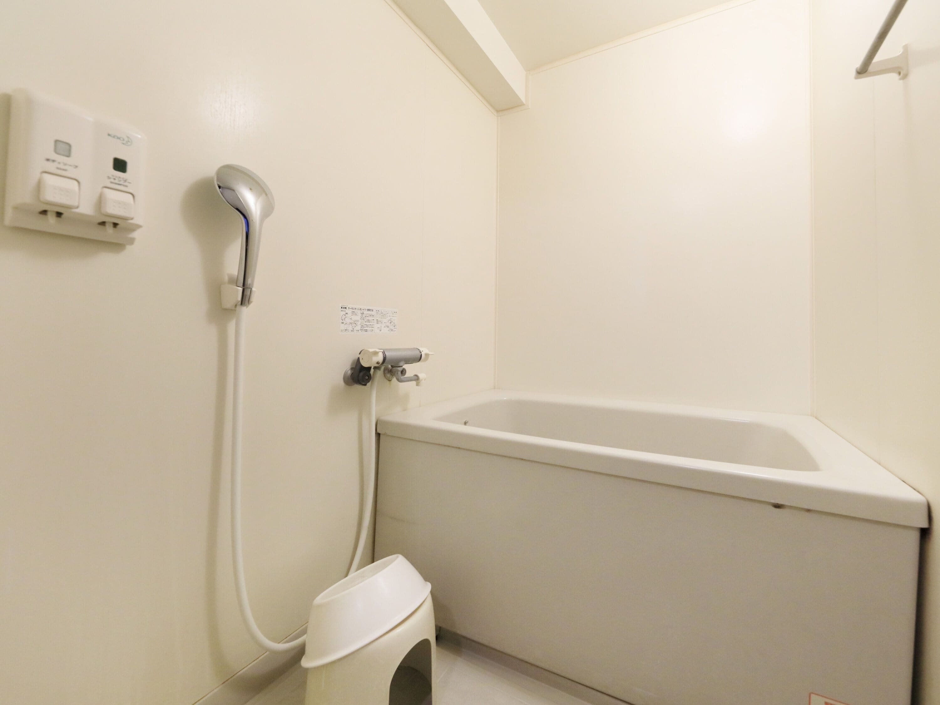 A bathroom with a white bathtub, a handheld showerhead, and a toilet.