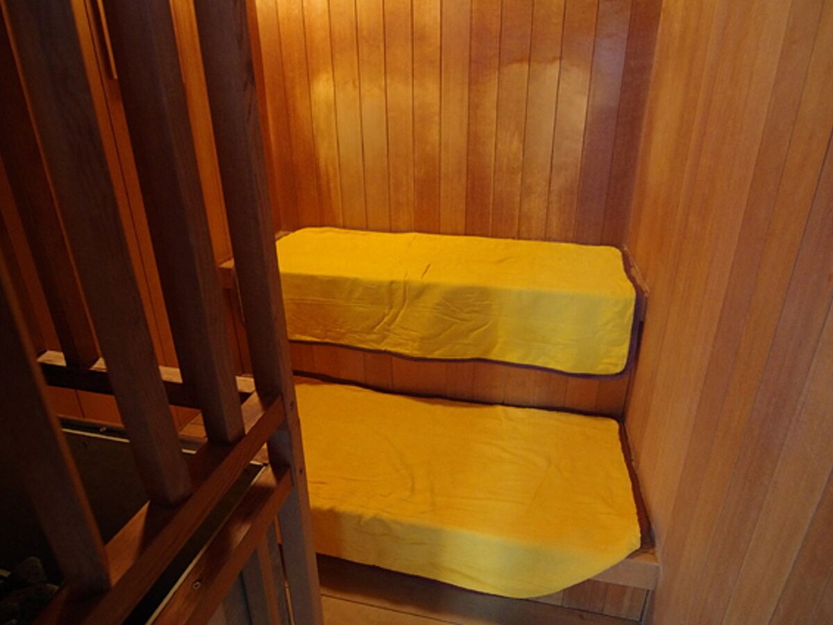 A wooden sauna with two benches covered in yellow towels.