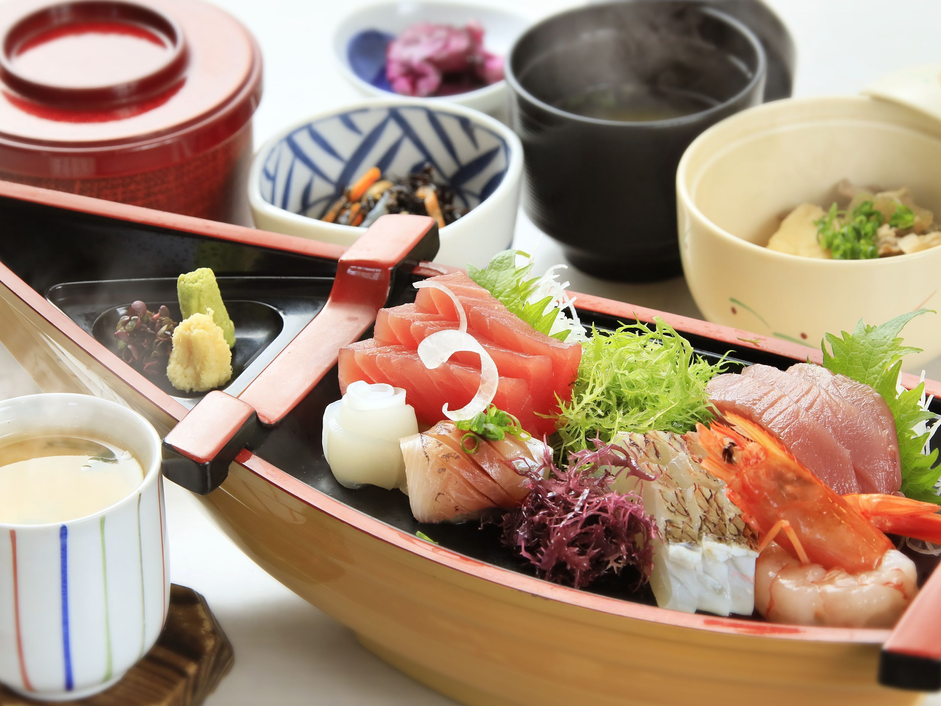 Een traditionele Japanse maaltijd met sashimi, groenten en een kleine kom soep.