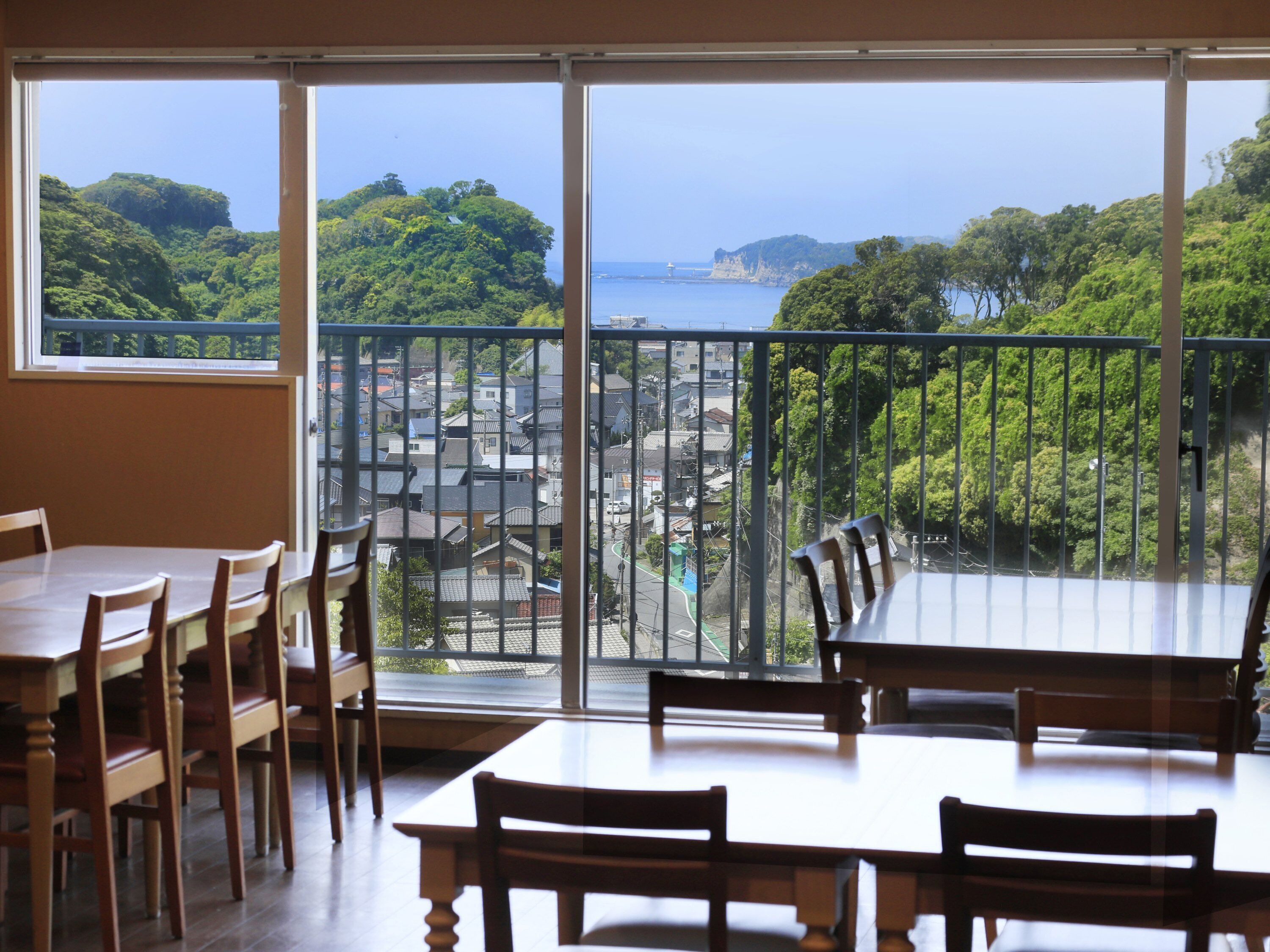 A dining area with a view of a coastal town and greenery.