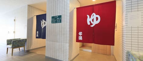 A hotel lobby with tiled walls, a reception desk, and a seating area.