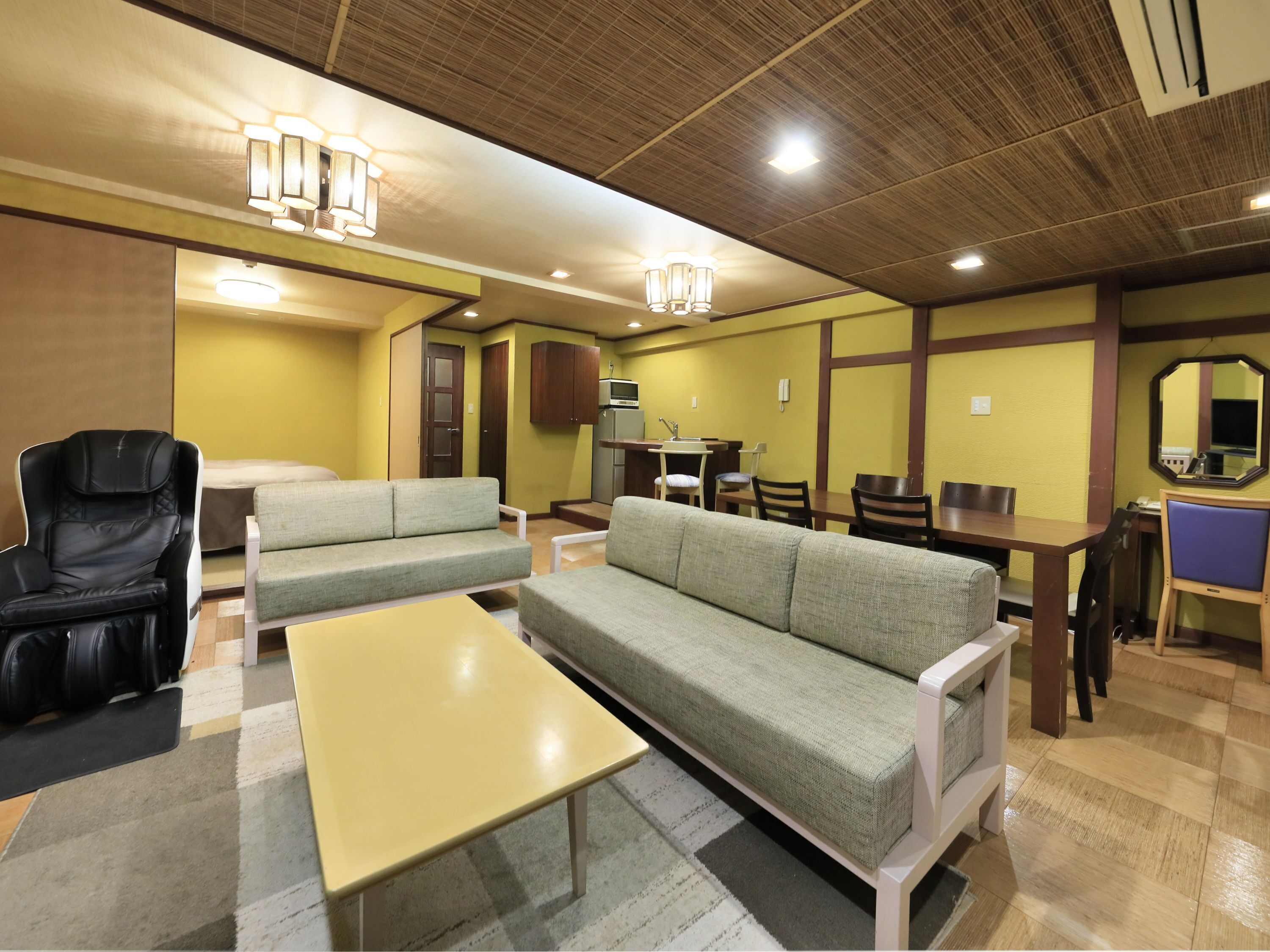 Una habitación con sofá, sillón, mesa y comedor con sillas y una mesa.