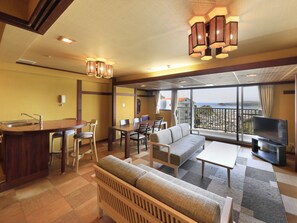 A hotel room with a balcony, a dining area, a sofa, and a TV. - Katsuura Hilltop Hotel & Residence (Katsuura)