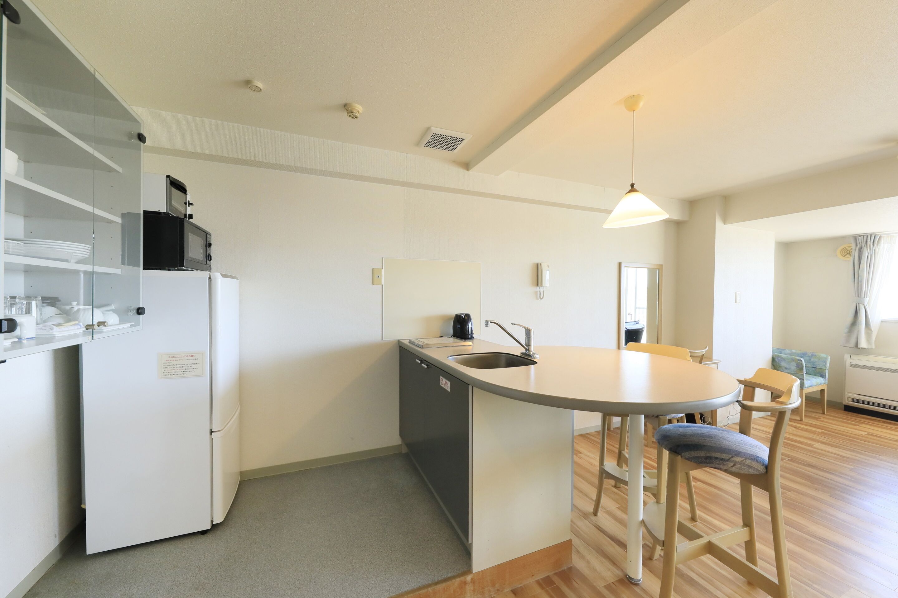 A compact kitchen with a refrigerator, microwave, sink, and a small dining area with chairs.