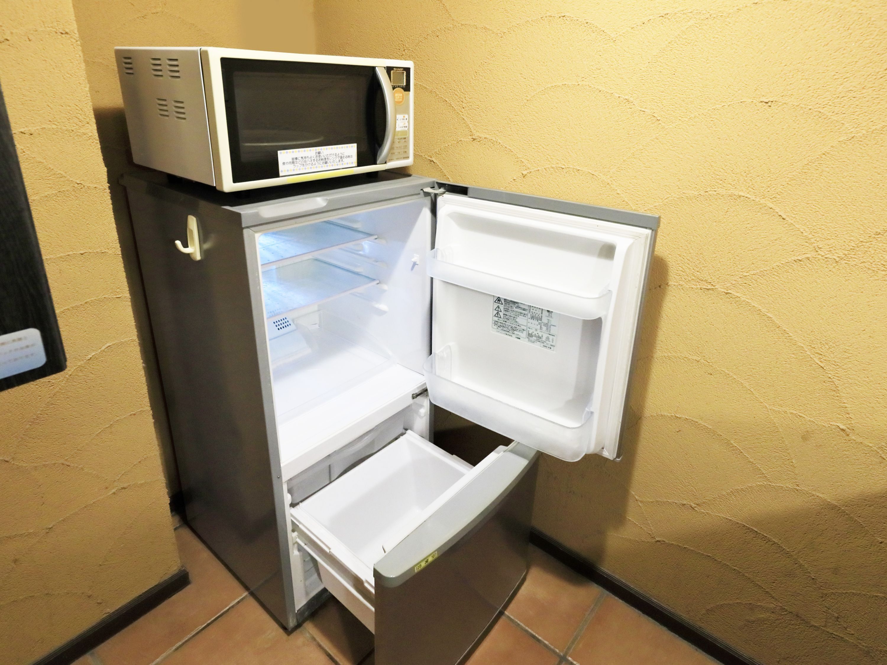 A compact refrigerator with a microwave on top, a freezer compartment, and a small refrigerator section.