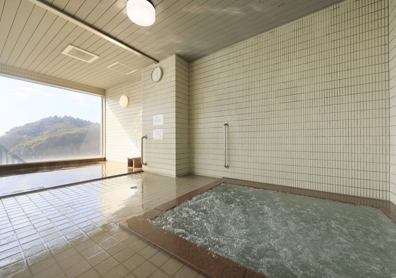 A large indoor swimming pool with a view of a mountainous landscape through a large window.