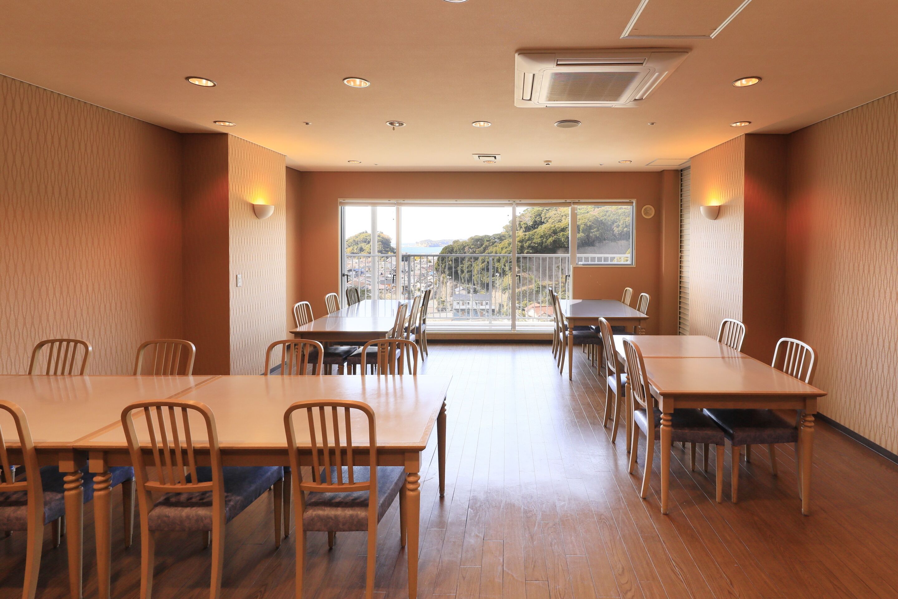 Una sala conferenze con diversi tavoli e sedie, ampie finestre che offrono vista sulla città e un soffitto con illuminazione a incasso.