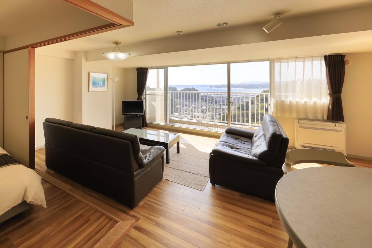 Et hotelværelse med seng, sofa, et lille bord og en balkon med udsigt.