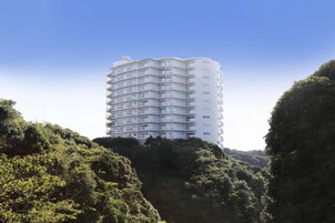 A multi-story hotel with balconies, surrounded by lush greenery.