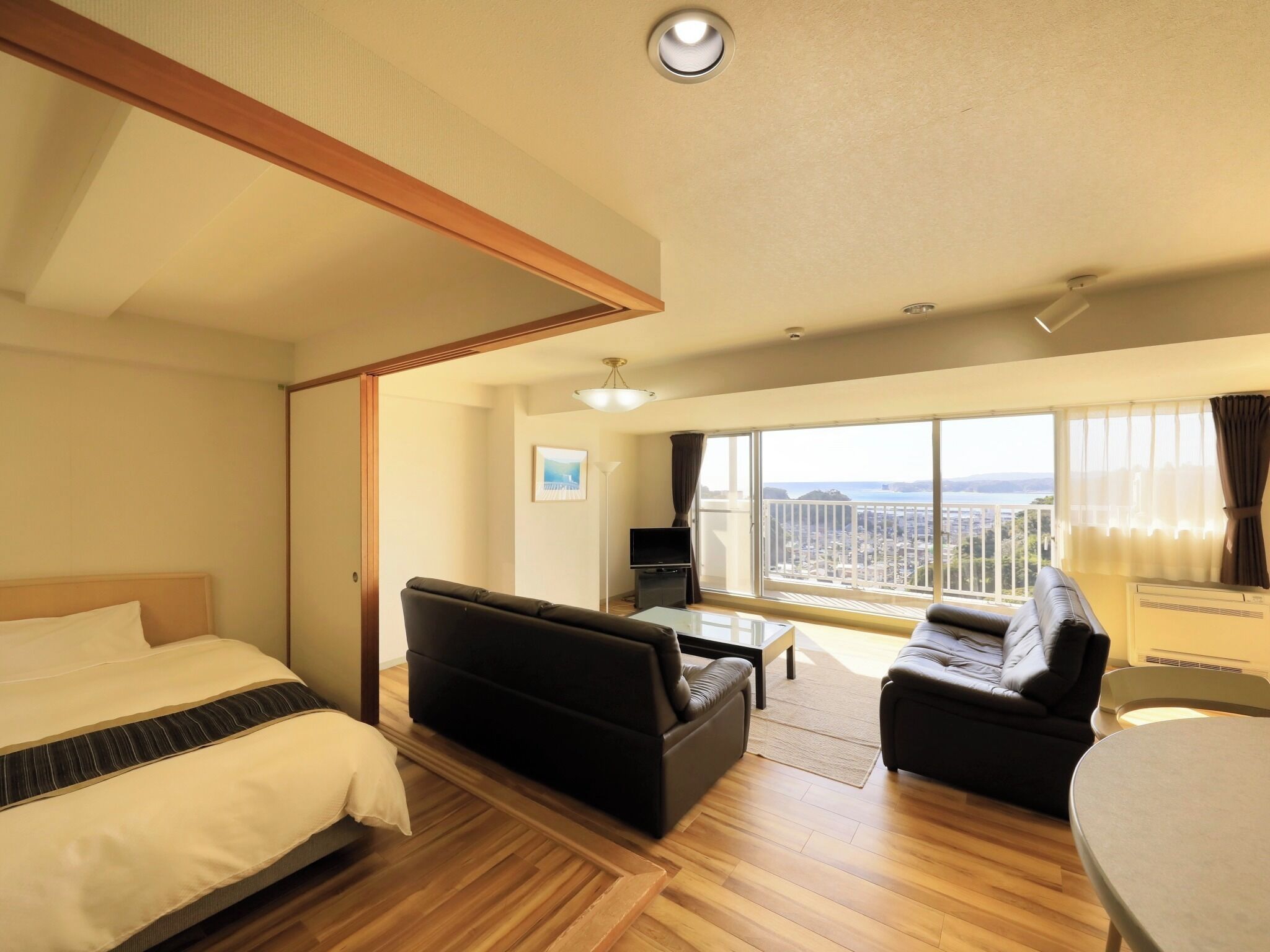 Ein Hotelzimmer mit Bett, Sofa, kleinem Tisch, Fernseher und einem Balkon mit Blick.