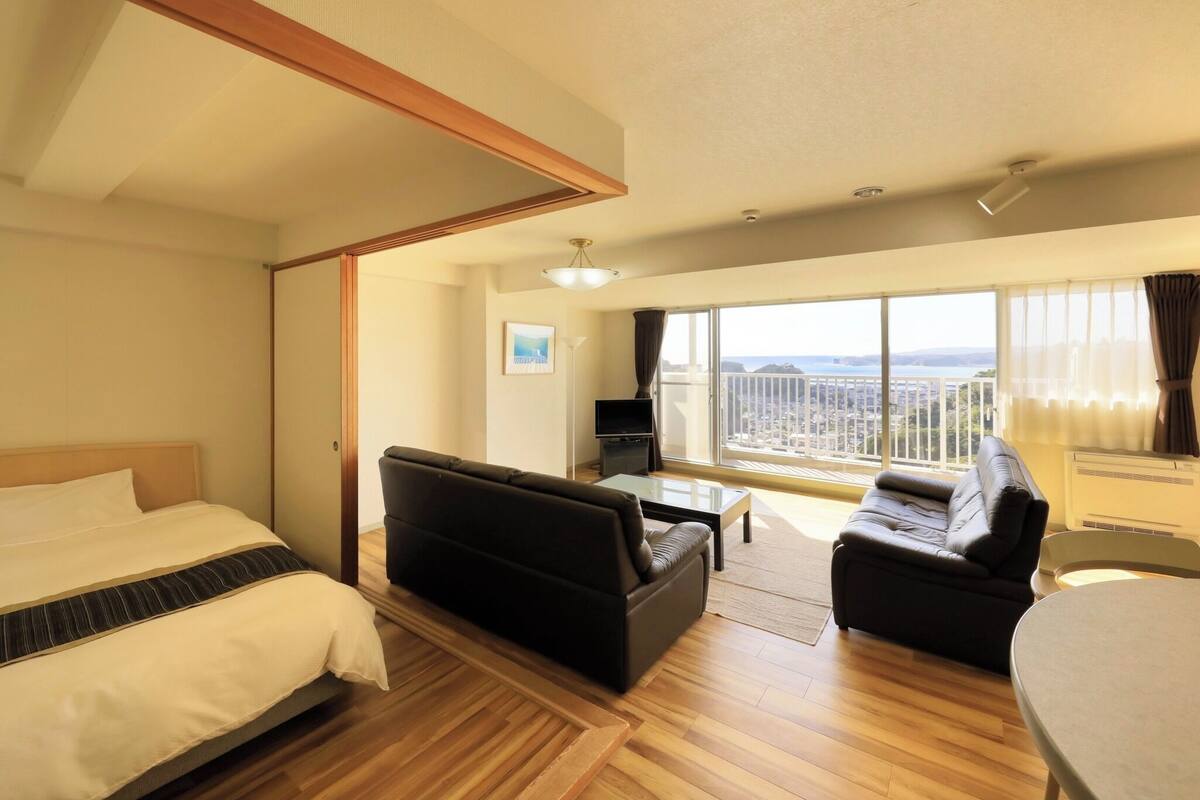 Et hotelværelse med en seng, en sofa, et lille bord, et fjernsyn og en balkon med udsigt.