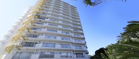 Un hotel de varios pisos con balcones, cielo despejado y palmeras.