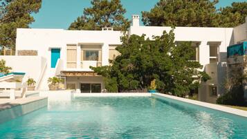 Una piscina al aire libre, sillones reclinables de piscina