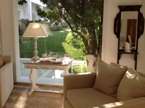 Una habitación acogedora con sofá, una mesa con lámpara y vistas a un jardín.
