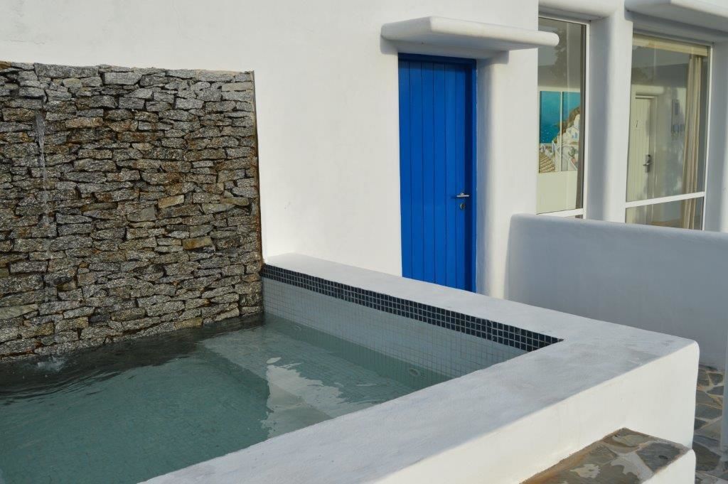 A stone wall, a blue door, and a swimming pool.