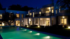 Un edificio moderno a più piani con piscina, area relax all'aperto e balconi illuminati.