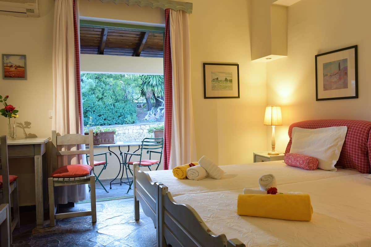 A hotel room with a bed, a desk, a chair, a window with curtains, and a lamp.
