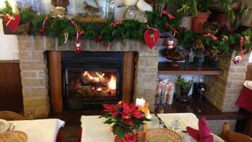 Una habitación acogedora con chimenea, una mesa lista para cenar y diversas decoraciones navideñas.