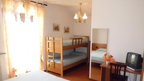 A room with bunk beds, a desk with a television, and a chair. - Albergo Canella (Fuipiano Valle Imagna)