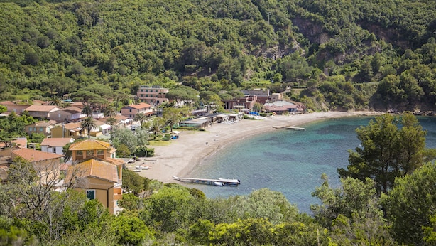 Une ville côtière avec une plage, des maisons et un bateau amarré près du rivage.