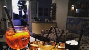 Un plateau contenant diverses boissons, notamment un martini, un mojito et une boisson au citron vert, dans un restaurant avec vue sur l’extérieur.