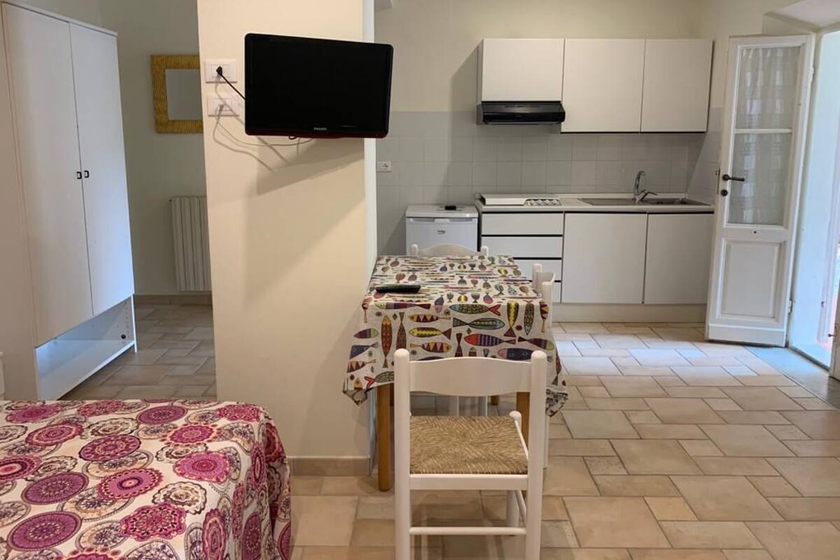 Una cocina compacta con armarios blancos, estufa integrada y un lavamanos.