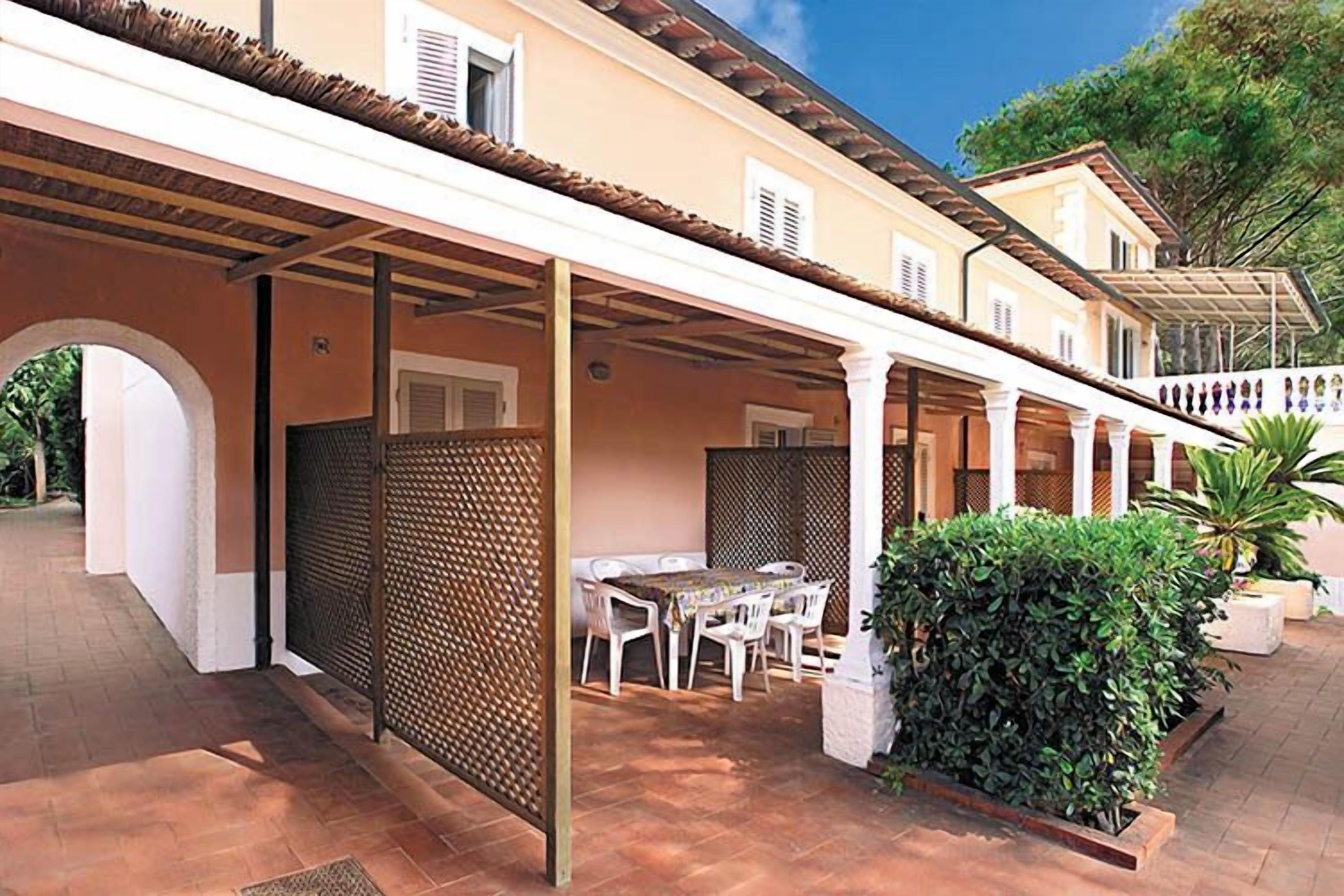 A covered outdoor patio with a table and chairs, a privacy screen, and a potted plant.