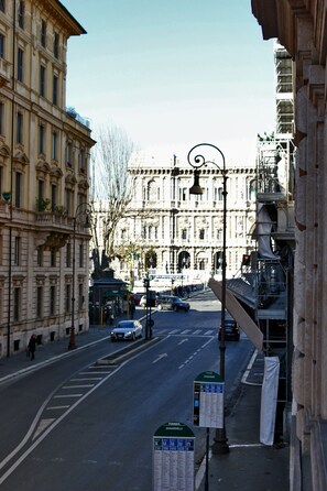A street view with a building featuring classical architecture, a clear sky, and a few cars on the road. - Residenza Zanardelli (Rome)