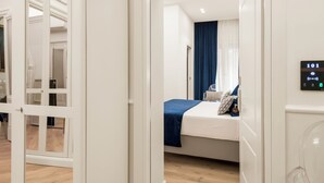 A hotel room with a bed, a bedside table, a digital control panel, and a view of the hallway. - Residenza Zanardelli (Rome)