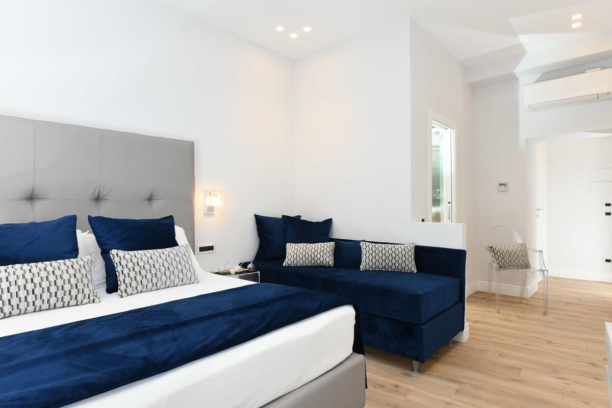 Un dormitorio moderno con una cama grande, dos camas más pequeñas y una zona de estar.