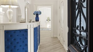 A reception area with a blue cushioned desk, a lamp, and a vase of flowers. - Residenza Zanardelli (Rome)