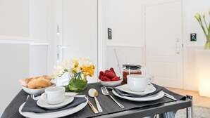 A breakfast setup with pastries, strawberries, and a coffee pot on a table with white plates, cups, and cutlery. - Residenza Zanardelli (Rome)