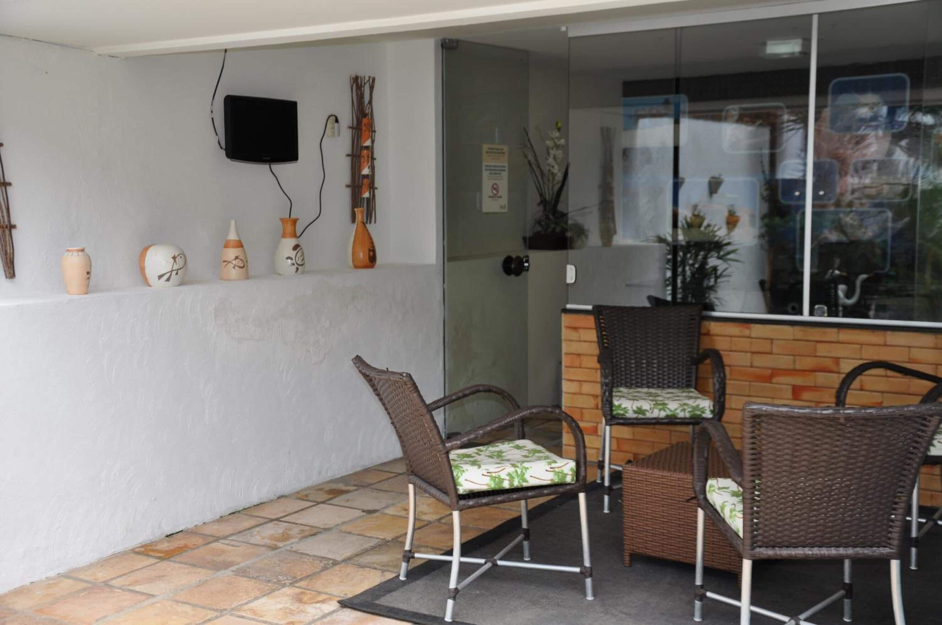 A patio area with wicker chairs and a small table, a wall-mounted TV, and decorative vases.