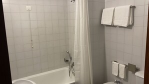 A bathroom with a shower, two sinks, and a toilet.